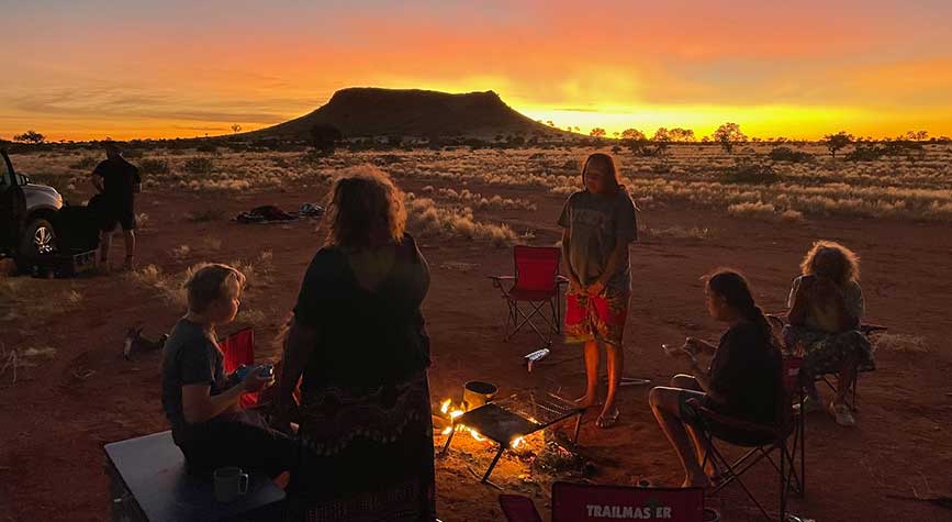 THE LAST NOMADS OF PINTUPI — People gathered around a fire at sundown
